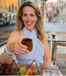 Susan Schwartz of a Lush Life Manual holding a drink at an outside table
