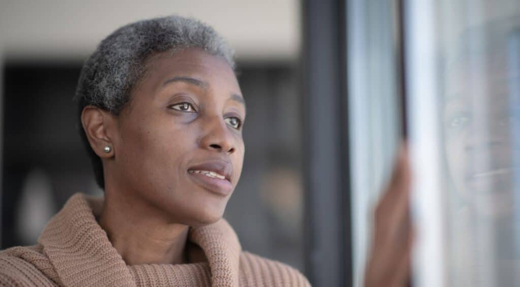 black woman with grey hair looking out the window