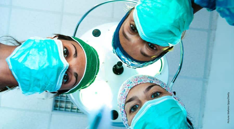 Doctors in scrubs looking down at patient