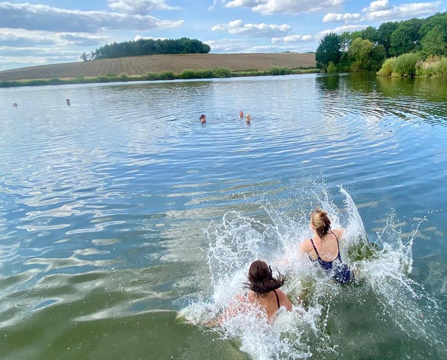 four midlife women swimming in a lake