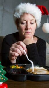 glum woman celebrating Christmas alone with TV dinner